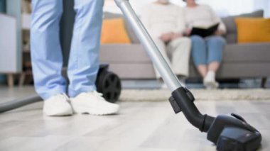 Sağlık görevlisi, yaşlı bir çifte odaları temizlemeleri ve yerleri süpürmeleri için yardım ediyor.
