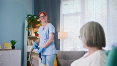 Yaşlı, genç, koruyucu eldivenli, yaşlı kadınların odasını süpüren kadın doktorla ilgilenmek.