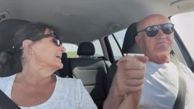 Tatildeki emekliler, mutlu, yaşlı ve evli bir çift yolculuk sırasında araba sürüyorlar.