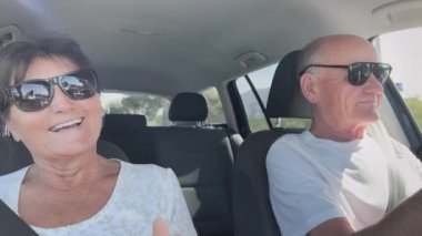 Aktif yaşlı evli çift güneşli bir günde arabayla seyahat ederken eğleniyor.