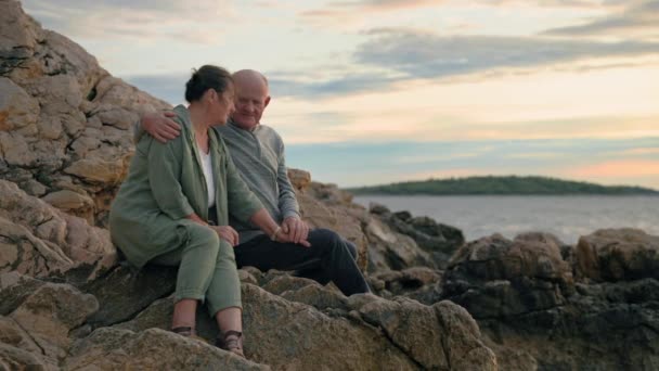 海で休暇を楽しむ魅力的な成熟した配偶者と一緒に日没の背景に座って — ストック動画