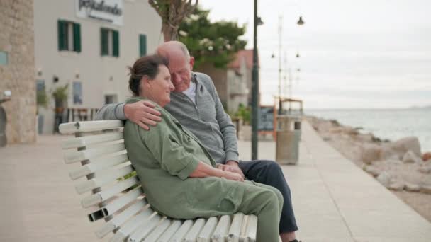 행복한 배우자는 따뜻한 바다의 전망을 즐기는 벤치에 포옹에 시간을 보내고 스톡 비디오