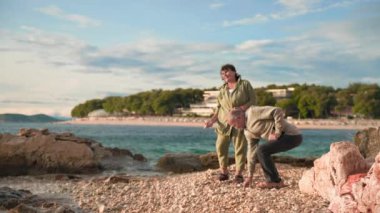 Aktif, yaşlı bir çift, deniz kenarında yürümekten ve ortak tatil sırasında suya taş atmaktan zevk alıyor.