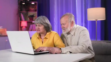Modern yaşlı karı koca, emekliliklerinde eğleniyor ve masada otururken bilgisayar oyunları oynuyorlar.