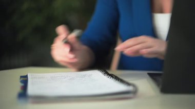 Ev ofisi, evde çalışan genç bir kadın dizüstü bilgisayarla notlar alırken odada oturuyor.