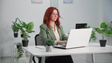 Yeşil ofis, genç bayan çalışan bitkilerle dolu bir ofiste dizüstü bilgisayarla çalışıyor.