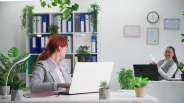 İş yerinde pozitif atmosfer, gülümseyen bayan meslektaşlar ofiste çalışırken kağıt ve uçak atıyorlar.