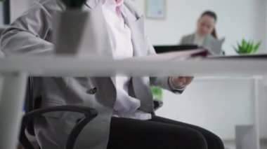 İyi bir çalışma ortamı, bilgisayarla çalışan genç bir kadın arka planda yeşil bitkilerle çalışan bir meslektaşla.