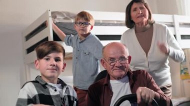 Modern aile eğlencesi, gözlüklü yaşlı bir adam ve arkadaşları ve yaşlı bir kadın rahat bir odada oturup bilgisayar oyunu oynarken eğleniyorlar.