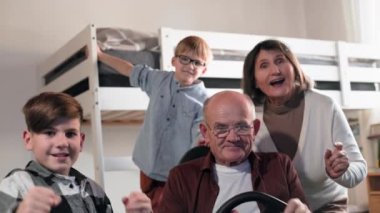 Aile eğlencesi, yaşlı bir adam yaşlı bir kadın ve çocuklarla birlikte çocuk odasında modern aletler kullanarak konsolda video oyunları oynarken eğleniyorlar.