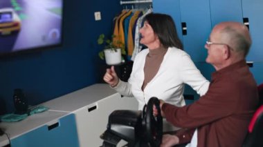 Modern yaşlı eşler odalarında oturan aletleri kullanarak konsolda video oyunu oynarken eğleniyorlar.