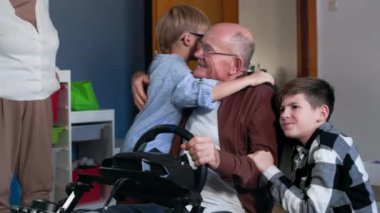 Aile ilişkisi, mutlu küçük çocuk büyükbabaya sarılıyor Playstation 'da oyun kazanırken evde dinleniyor.