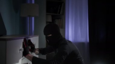 Tehlike, kar maskeli adam ve eldivenli adam dairede para ve değerli eşyalar aramak için etrafı karıştırıyor.
