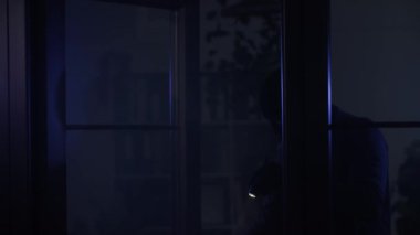 Soygun, kar maskeli erkek hırsız elinde fenerle geceleri değerli eşyalar aramak için mekanı inceliyor.