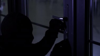 Hırsızlık, kar maskeli erkek suçlu elinde ana anahtarla gece kapı kilidini açar, yakın plan.