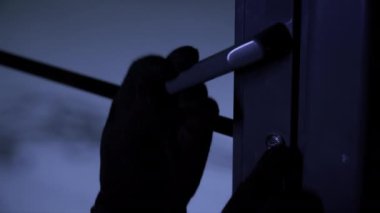 Eve zorla giren, elinde ana anahtar olan eldivenli bir adam geceleri kapıyı açar, yakın plan.