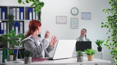 Mutlu genç bayan meslektaşlar iş gününün sonunda kağıt uçaklarla oynarken eğleniyorlar.