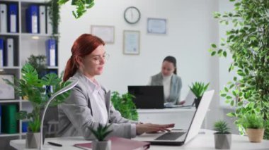 Genç bayan çalışan, ofiste bilgisayar üzerinde çalışırken iş arkadaşından gelen belgelerin olduğu klasörü alıyor.