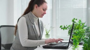 Ofiste masa başında çalışırken bilgisayarın klavyesinde yazan kadın.