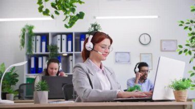 Başarılı bir anlaşma, genç bayan ve erkek meslektaşlar ofiste bilgisayar başında müşterilerle konuşurken, siyahi bir adam sevinçle bağırıyor üretken bir çalışma sayesinde masadan kalkar.