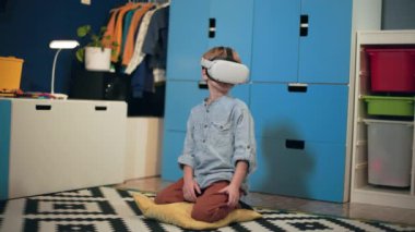 Modern teknoloji, sanal gerçeklik gözlüklü küçük çocuk çocuk çocuk odasında oturuyor.