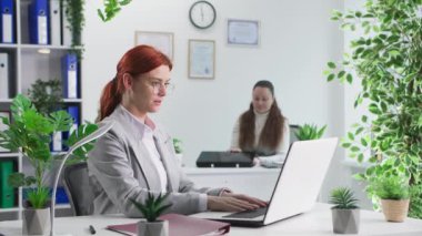 Ofiste çalışma ortamı, gözlüklü bir kadın iş sırasında iş arkadaşıyla bilgisayarla çalışıyor.