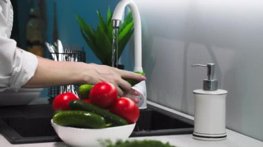 Ev işleri, kadın eli mutfak lavabosunda yemek yapmadan önce taze sebzeleri yıkıyor.