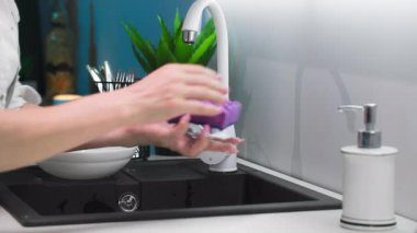 Günlük ev rutini, sünger ve köpük kullanan kadın eli mutfak lavabosunda bulaşık yıkıyor, kapat.