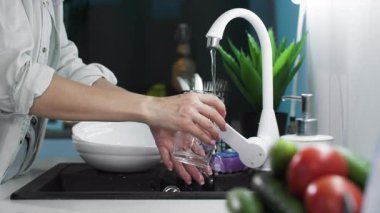 Mutfakta temizlik, kadın eli bardağı yıkıyor ve musluk suyuyla duruluyor, yakın plan.