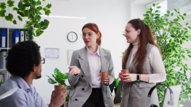 Kahve molası, genç bayan ve erkek çalışanlar ofiste birbirleriyle konuşarak eğleniyorlar.