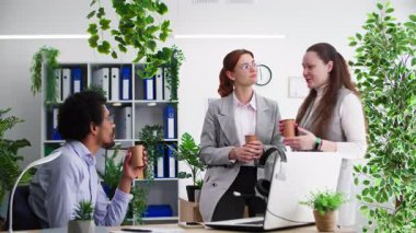 İş ilişkileri, kadın ve erkek iş arkadaşları ofiste kahve molası sırasında sohbet ediyorlar.