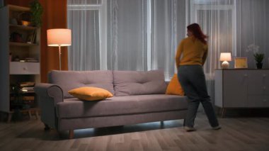 Akşamları, sarı kazaklı mutlu kızıl saçlı kadın oturma odasındaki kanepeye sıcacık, loş bir ışıkla atlar. 