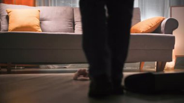 Kot pantolonlu ve botlu bir kadın odanın bir ucundan diğer ucuna yürür, ceketini, çantasını yere bırakır ve botlarını çıkarır. Kanepeye gider, ev ayakkabılarını giyer, kanepeye oturur. Şey...