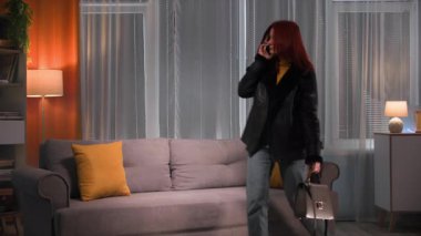 Akşamları, işten sonra ev kıyafetleri ve ev ayakkabıları ile yorgun genç bir kadın evine gelir ve kanepede oturur. Çantasini birakti ve telefonda konusmaya basladi.