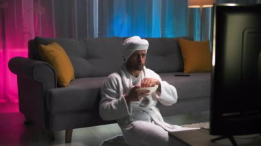 Adamın keyfi yerinde, dikkatle ekranda olanları izliyor, gösterinin ve patlamış mısırın tadını çıkarıyor. Televizyonda olan her şey onun yüzüne duygusal olarak yansıyor. Yaşıyor.