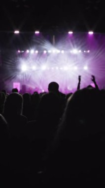 El sallayan hayranların karanlık silueti. Hayranlardan biri alkışlıyor. Magenta sahne arkası gösterisi, hayranların en sevdiği rock grubu sahnede