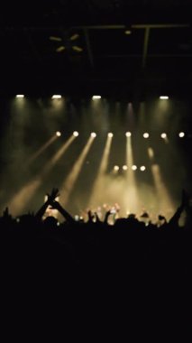 Ön plandaki kadın, el sallayarak ve dans ederek sahnenin sarı ışıklarına karşı.