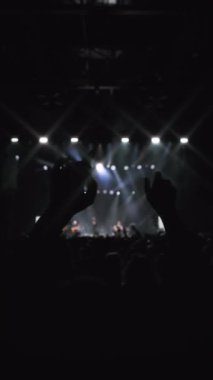 Konser gösterisi. Sahne arkasında el sallayan dans eden kadının karanlık silüeti. Onun güçlü duyguları var. Taraftarların en sevdiği rock grubuyla beyaz ve mavi arka plan gösterisi