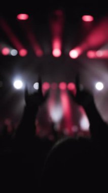 Konser müzik şovu. El sallayan hayranların karanlık silueti. Önplanda genç kadınlar yükselen eller ve güçlü duygularla dans ediyorlar. Aktif olarak elleriyle ilahi söylüyor. Magenta ve beyaz