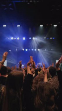 Ön planda el çırpan kadın ellerle alkışlayan bir hayran topluluğu. Taraftarların kalabalığı periyodik olarak beyaz ışıkla aydınlatılıyordu. En sevdikleri rock grubu sahnede beyaz ve...