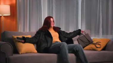 Akşamları, işten sonra giysisi ve botlarıyla yorgun, güzel kızıl saçlı bir kadın yumuşak bir kanepeye oturur, botlarını çıkarır ve onları odada fırlatır. Yumuşak bir kanepede dinleniyor.