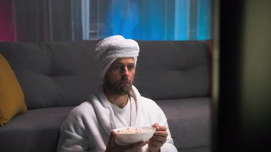 Beyaz bir bornoz ve havluyla duştan sonra çekici bir adam, o iyi bir ruh hali içinde, patlamış mısır yiyor ve sakince bir televizyon programının tadını çıkarıyor. Aniden, ekranda olanlar onu gerçekten şaşırttı. O