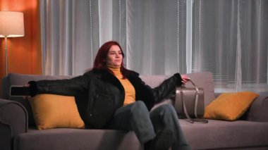 Akşamları, işten sonra giysisi ve botlarıyla yorgun, güzel kızıl saçlı bir kadın yumuşak bir kanepeye oturur, botlarını çıkarır ve onları odanın her yerine fırlatır. Yumuşak bir kanepede dinleniyor.