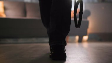 Dış giysisi ve botları ile bir kadın odanın diğer ucundan kanepeye yürür, yol boyunca çantasını ve ceketini yere bırakır, sıcak, loş bir ışıkla oturma odasında. Odaklanmanın sonu