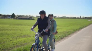 Yaşlı bir çift iki koltuklu bisiklet üzerinde egzersiz yapıyor. Onlar sıcak bahar güneşli havada güzel bir kırsal alanda bir yol boyunca at sürüyorlar. Geziden bir sürü izlenim edindim.