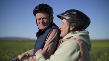 Yaşlı, emekli bir çift kır çiçekleriyle dolu bir tarlada yürüyorlar, adam bisikletle yürüyor, kadın erkeğin elini tutuyor, konuşuyorlar, hayattan zevk alıyorlar ve birbirlerine eşlik ediyorlar.