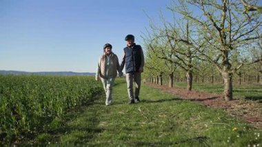 Şehrin dışındaki bir dinlenme tesisinde, yaşlı bir çift şehir dışında, bir tarlanın kenarındaki yeşil çimlerin üzerinde, meyve ağaçlarını geçerek yürüyor. Yaşlı kadın adamın yanında yürüyor, elinde tutuyor.