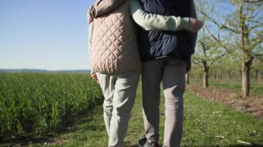 Şehrin dışındaki bir dinlenme tesisinde, yaşlı bir çift bir tarlanın kenarındaki yeşil çimenler boyunca geziniyor, meyve ağaçlarının yanından geçiyor. Kadın ve erkek senkronize bir şekilde yürür ve birbirlerini kucaklarlar. Düşük görüntü görüntüsü