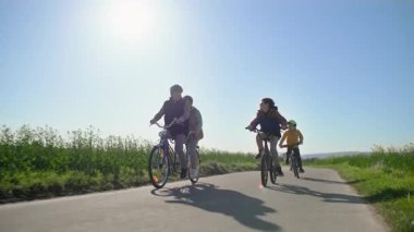 İki koltuklu bisiklet süren emekli bir çift torunlarıyla kır çiçeği tarlalarının arasında geziyor. Bisikletli torunlar, büyük anne ve büyük babaların sakin evcil hayvanlarını kolayca geçebilir.