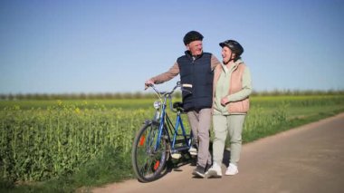 İki koltuklu bir bisikletten inen yaşlı bir çift, kırsal bir yolda yavaşça yürüyor. Erkek ve kadın yan yana yürür, kucaklaşır ve gezi hakkındaki izlenimlerini tartışırlar.